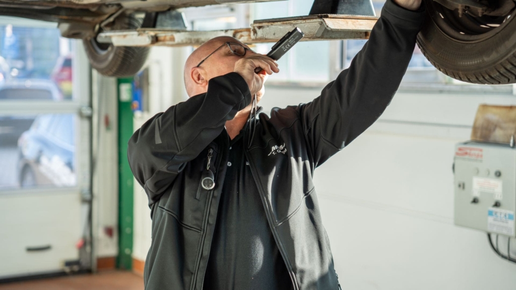 Serviceberater bei Kontrolle eines Fahrzeugunterbodens