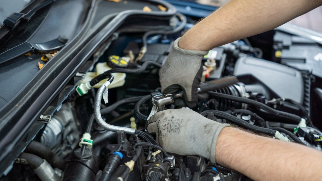 KFZ Mechatroniker arbeitet an einem Motor