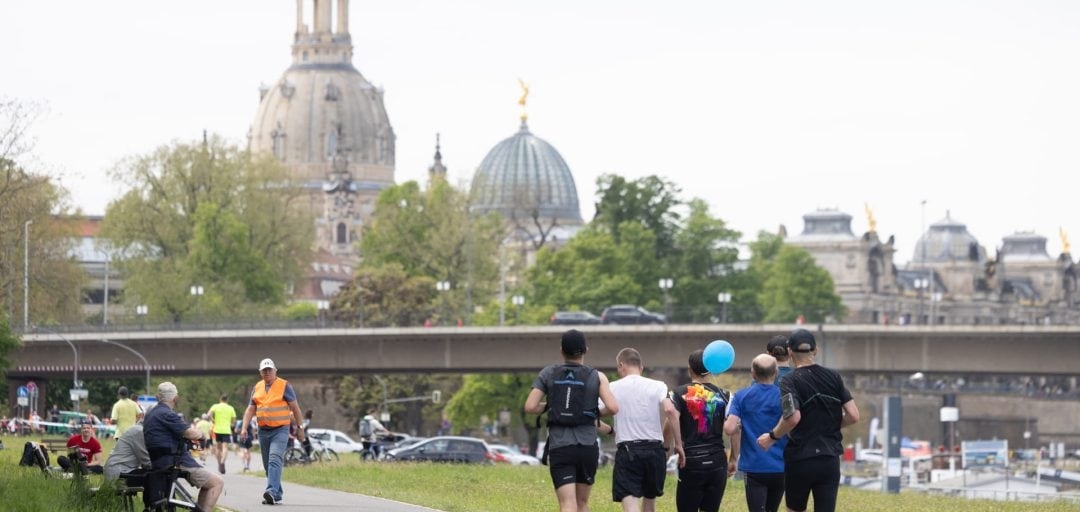 Läufer vor der Carolabrücke mit Blick auf die Frauenkirche Dresden