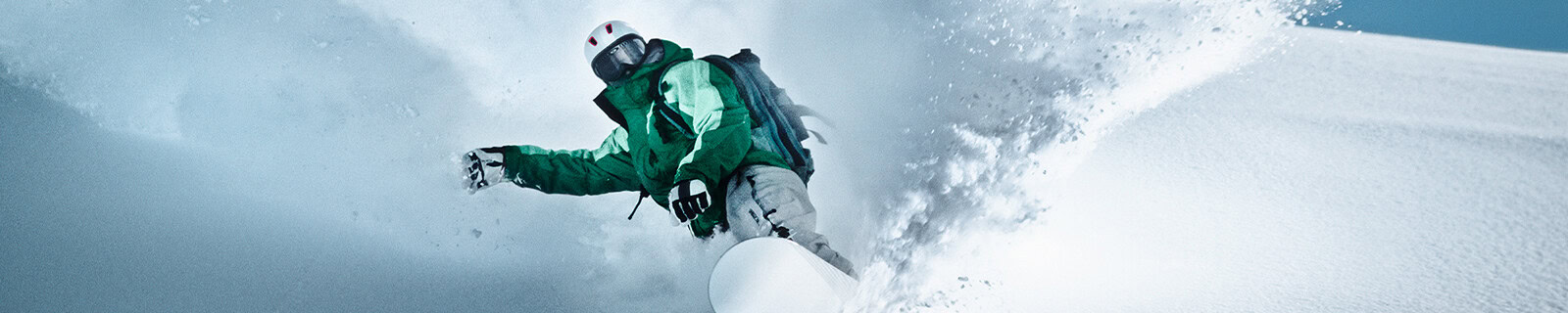 Snowboarder in grüner Skikleidung auf Skipiste